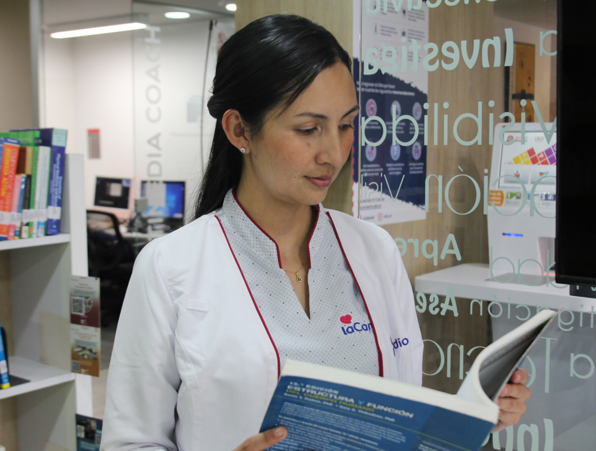 Médica de la Fundación Cardioinfantil leyendo un libro de medicina en la biblioteca del centro médico - LaCardio